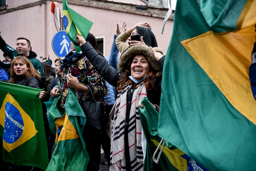 Gritos de Manifestantes com bandeiras do Brasil em mãos comemoram com sorrisos a chegada do presidente brasileiro à cidade italiana