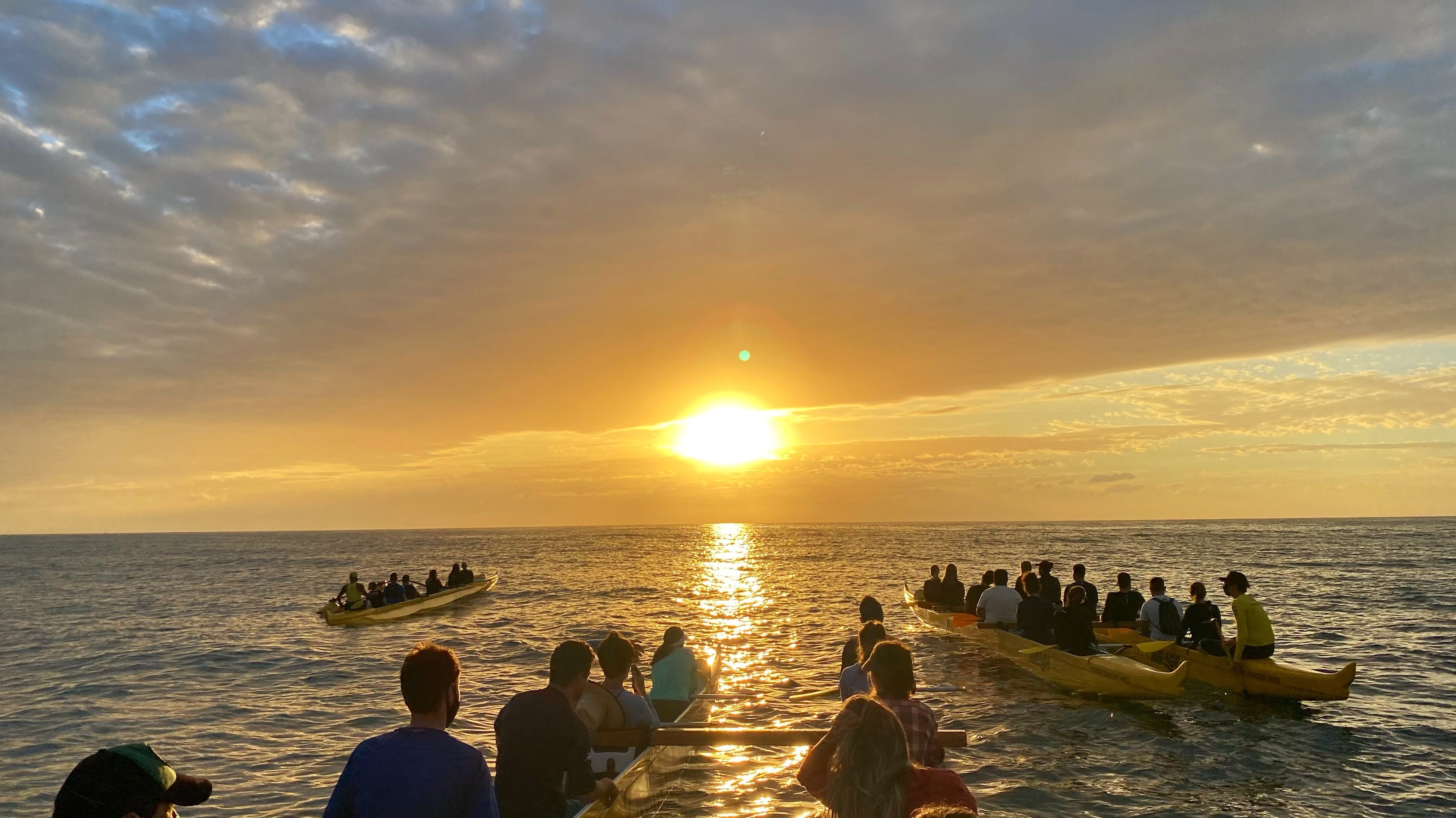 O nascer e o pôr do sol são alguns dos roteiros mais procurados na Kanaloa Va’a, com até 30% de desconto para sócio do Clube NSC Pessoas observando o pôr do sol no meio do mar a bordo de canoas havaianas da Kanaloa Va'a