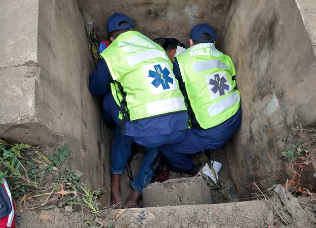 Idoso recebendo atendimento pelos bombeiros dentro do bueiro