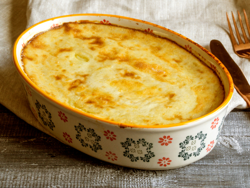 Escondidinho de camarão Travessa branca com escondidinho e queijo derretido